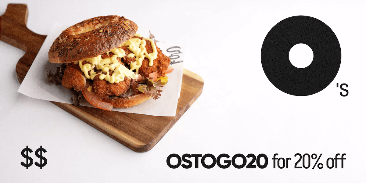 a chicken schnitzel bagel with tomatoes on a wooden platter with Bagel O's logo and $$ with the promo code for 20% off