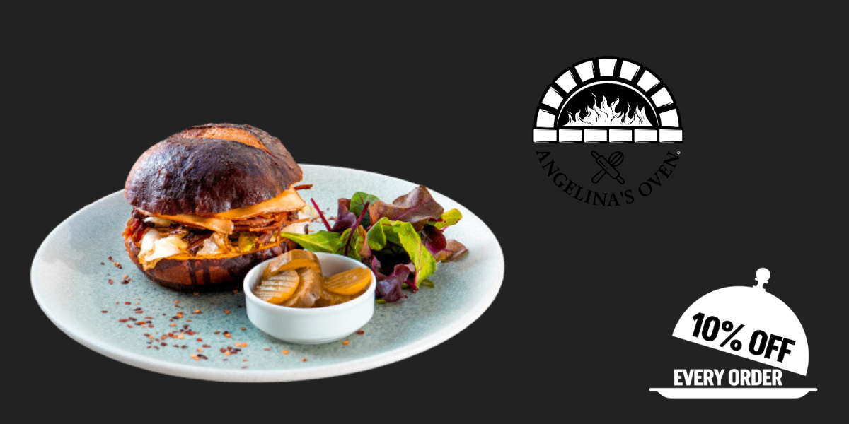 Brisket sandwich on a plate with a salad and pickles from Angelina's Oven with the 10% off icon